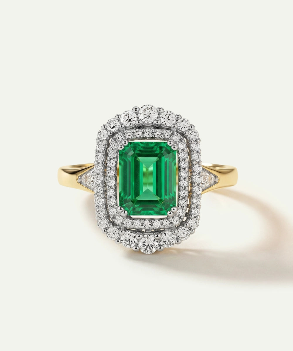 Emerald ring with diamond halo on a white background