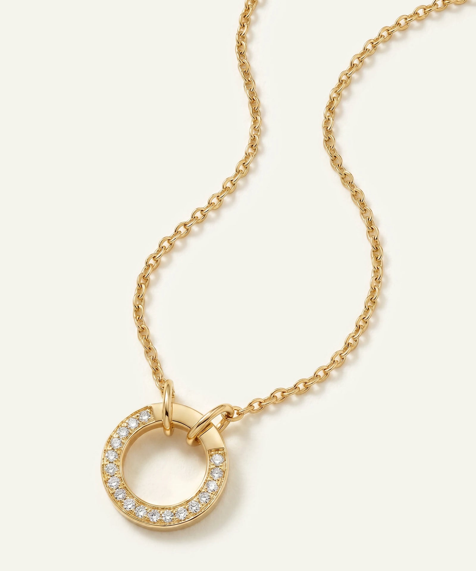 Gold necklace with a circular pendant on a white background