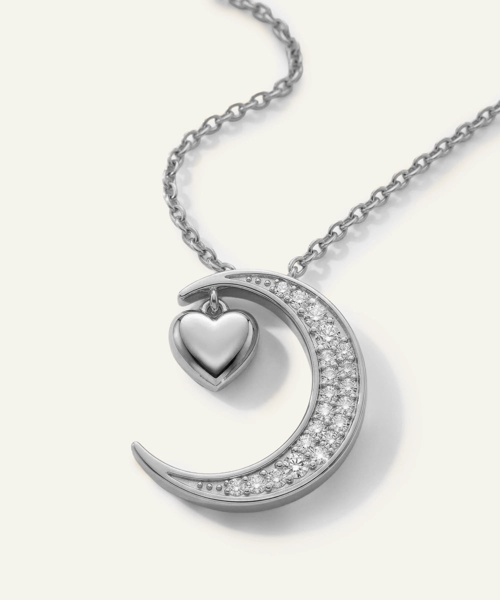 Silver necklace with a crescent moon and heart pendant on a white background