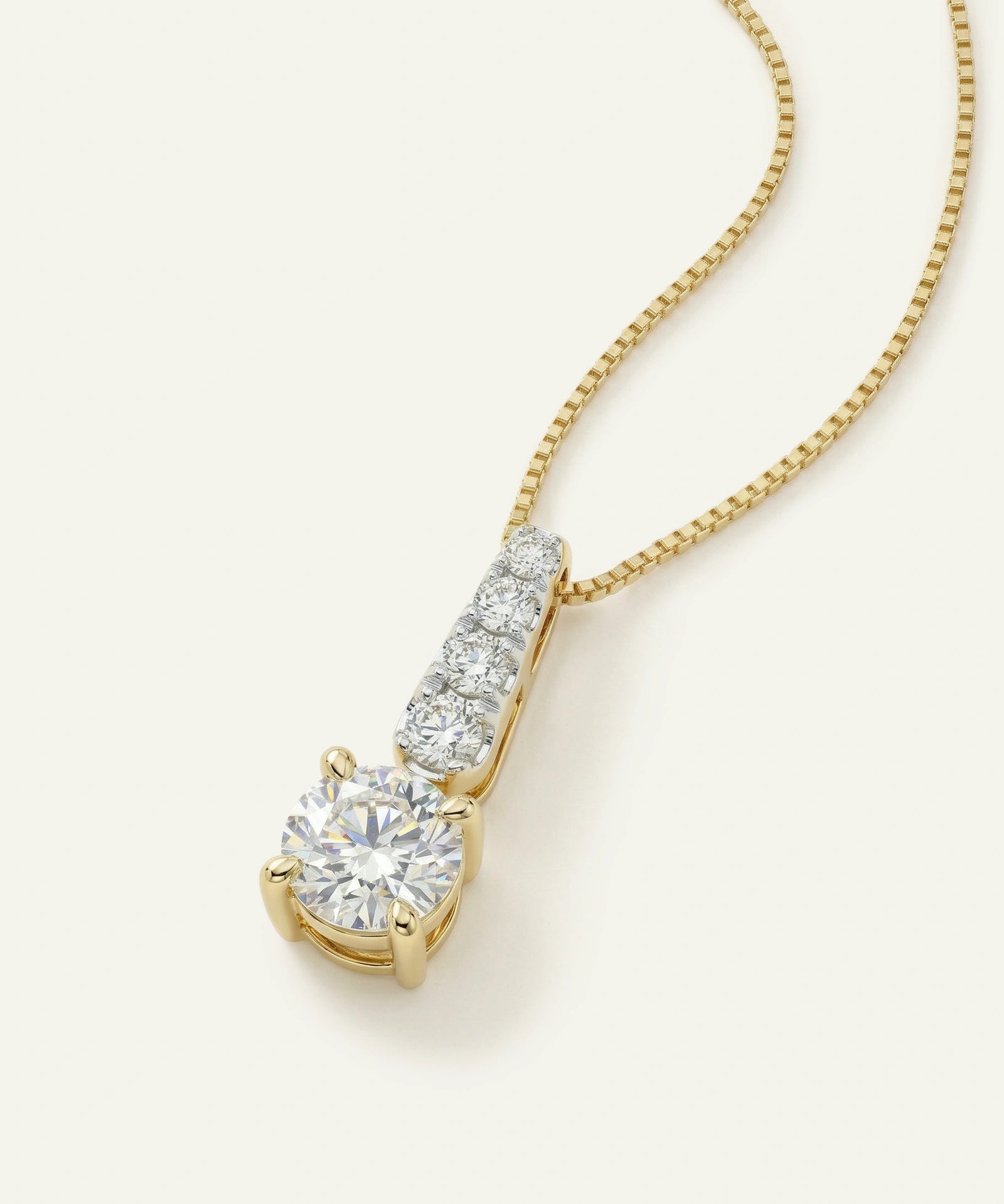 Gold necklace with a diamond pendant on a white background