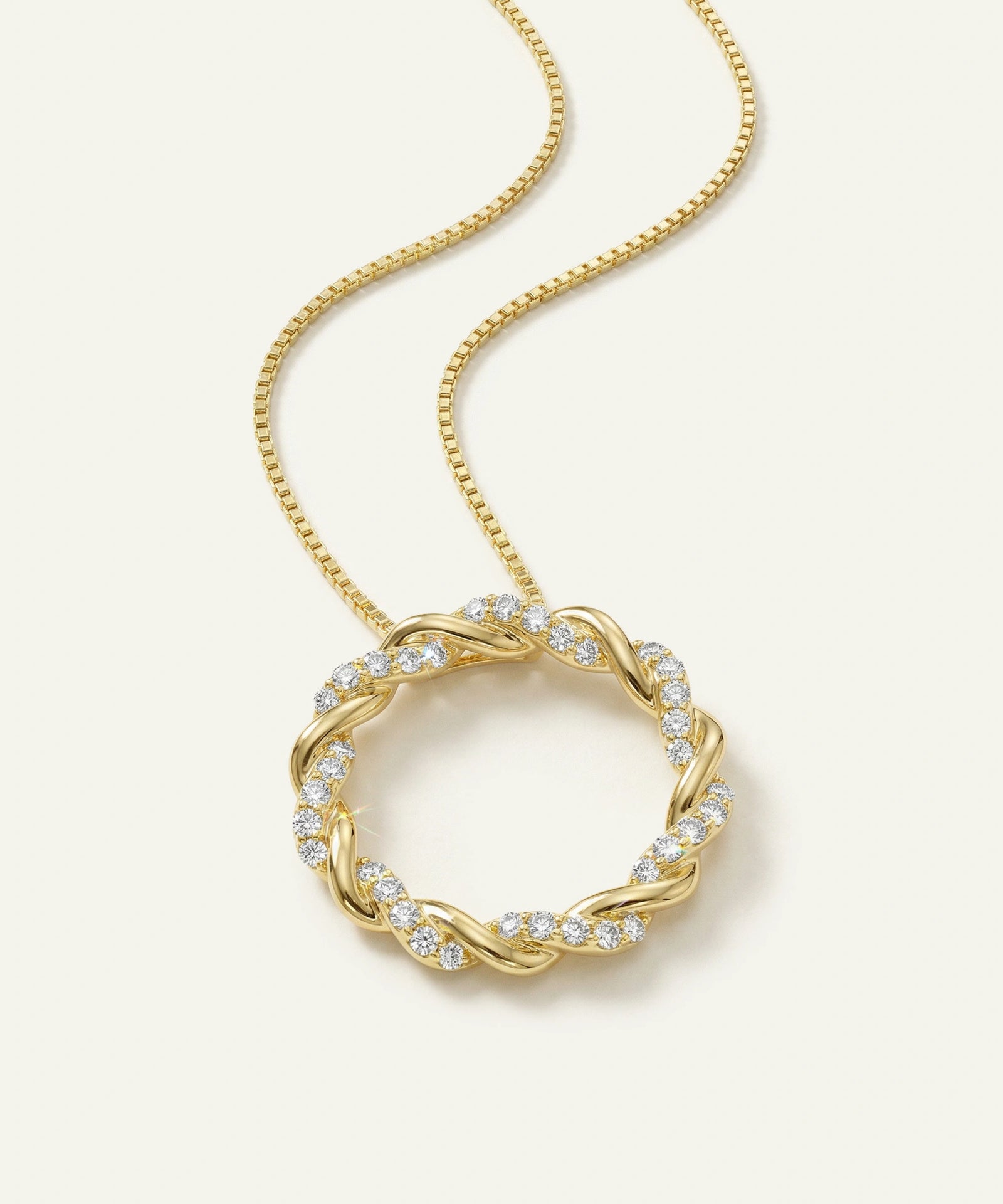 Gold necklace with a circular pendant on a light beige background