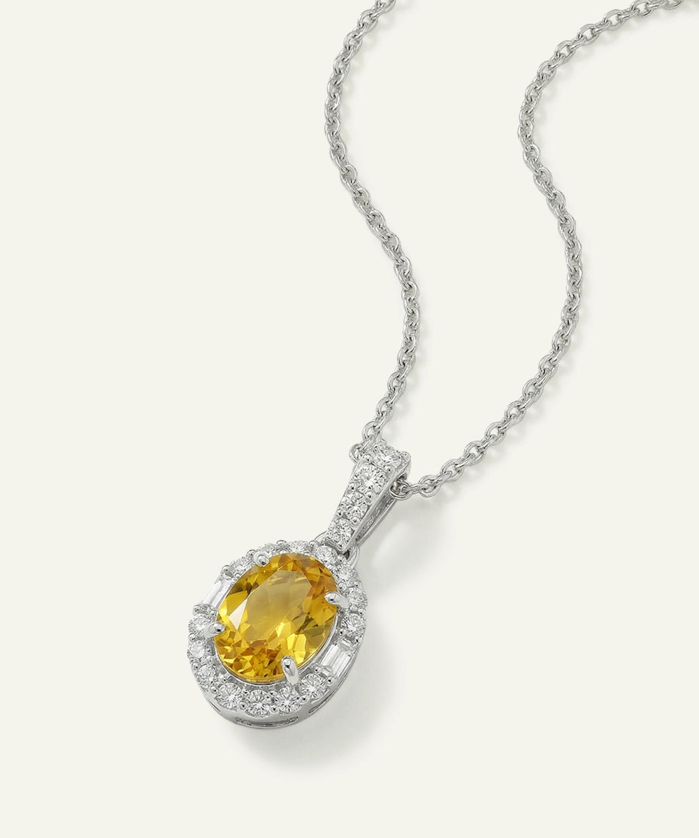 Silver necklace with a yellow gemstone pendant on a white background