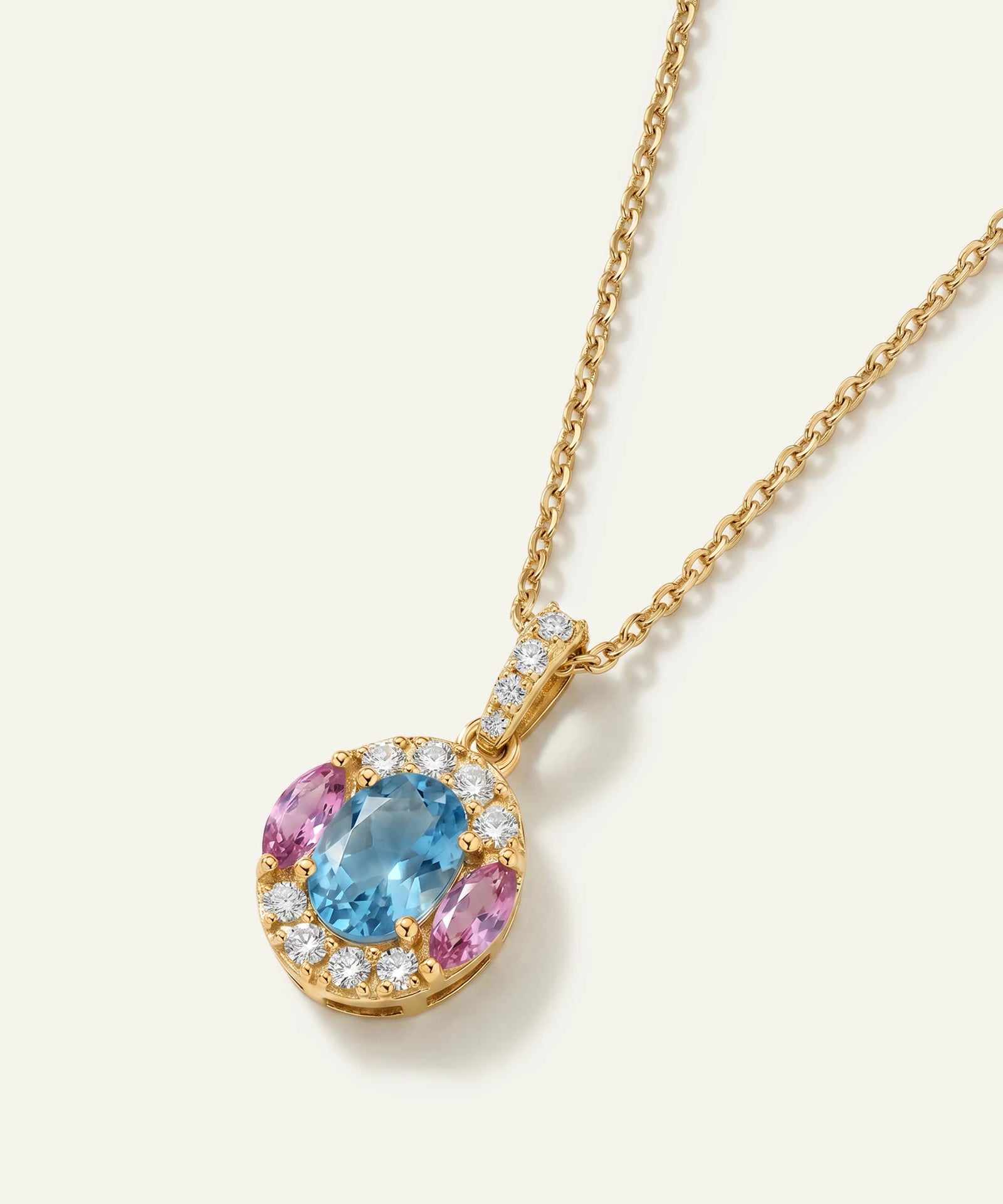 Gold necklace with a pendant featuring a blue gemstone and pink stones on a white background