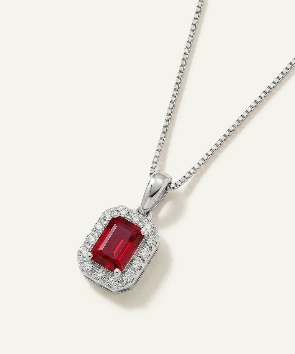 Silver pendant with a red gemstone on a white background