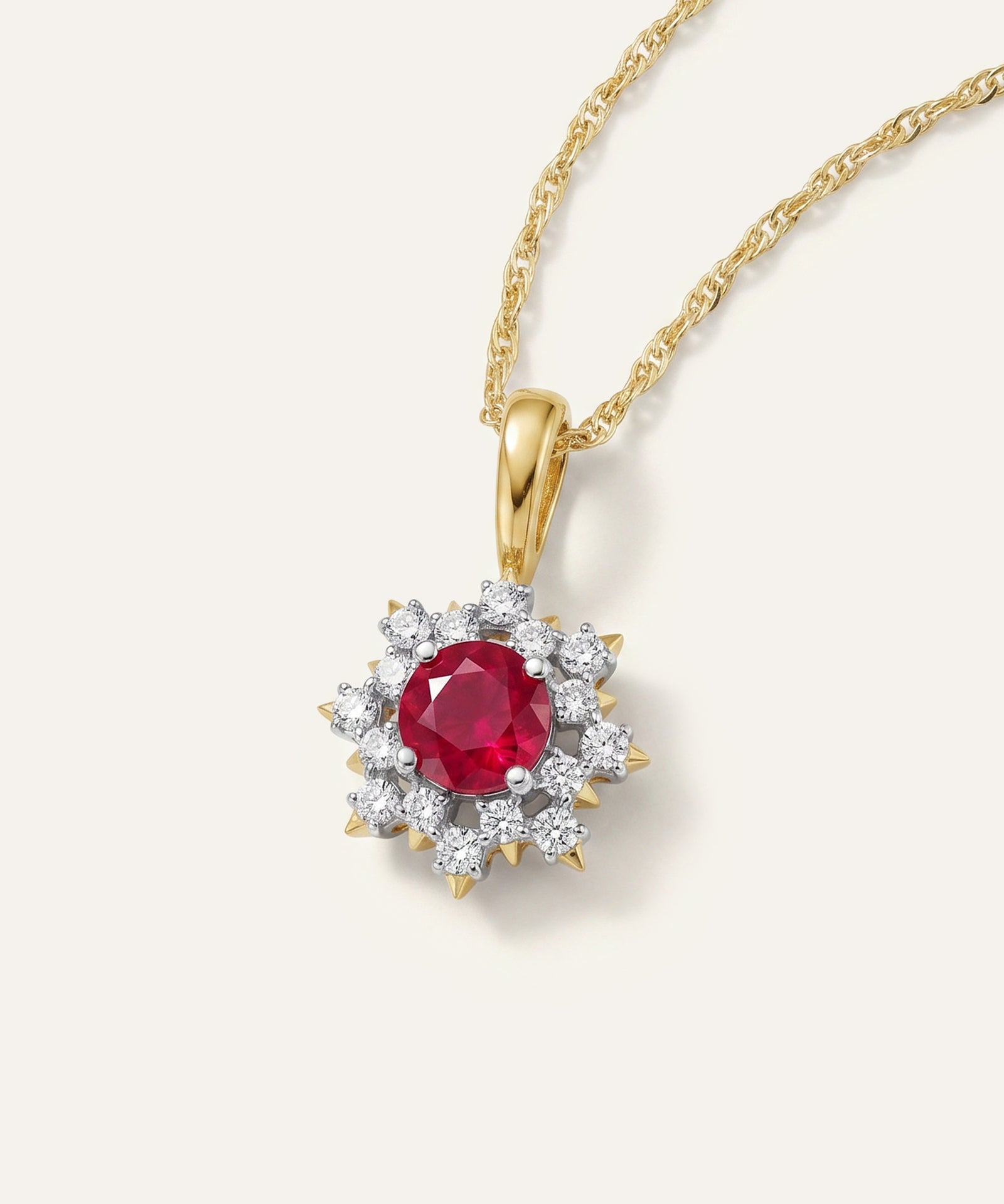 Gold pendant with a red gemstone and diamond accents on a white background