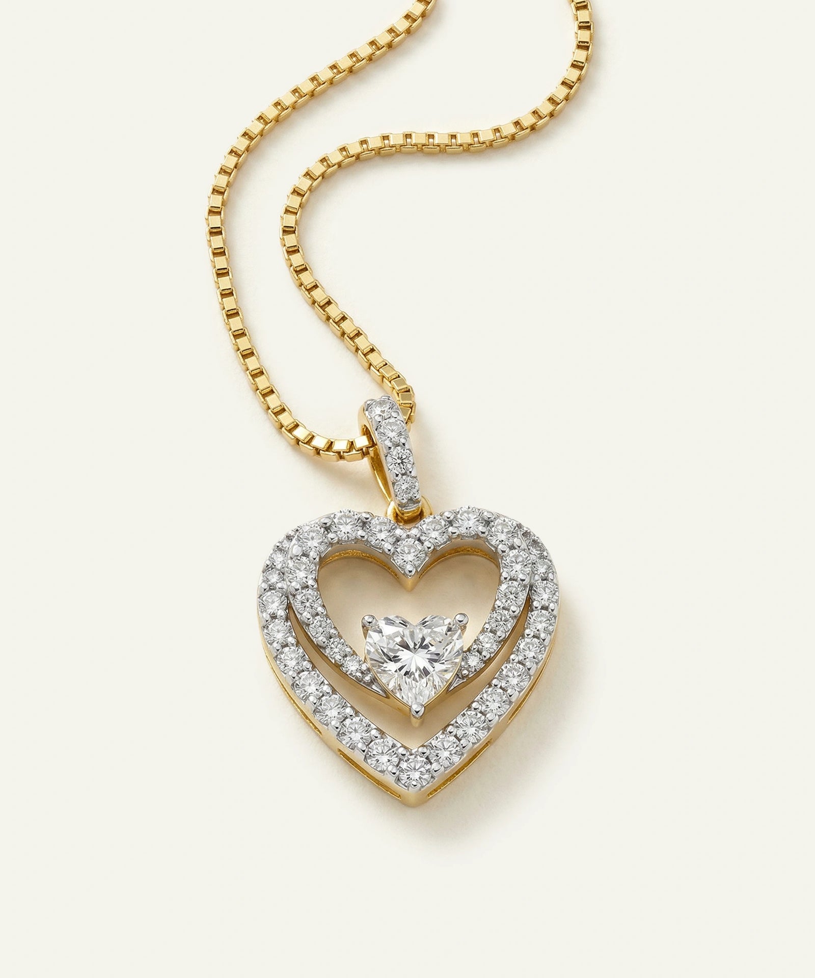 Gold heart-shaped pendant with diamonds on a white background