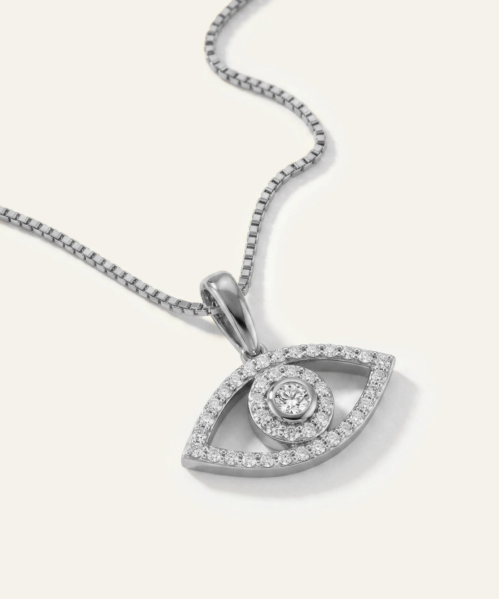 Silver eye-shaped pendant with diamonds on a white background