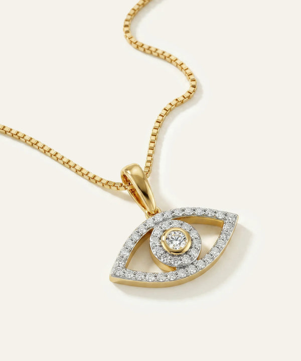 Gold necklace with an eye-shaped pendant on a light beige background