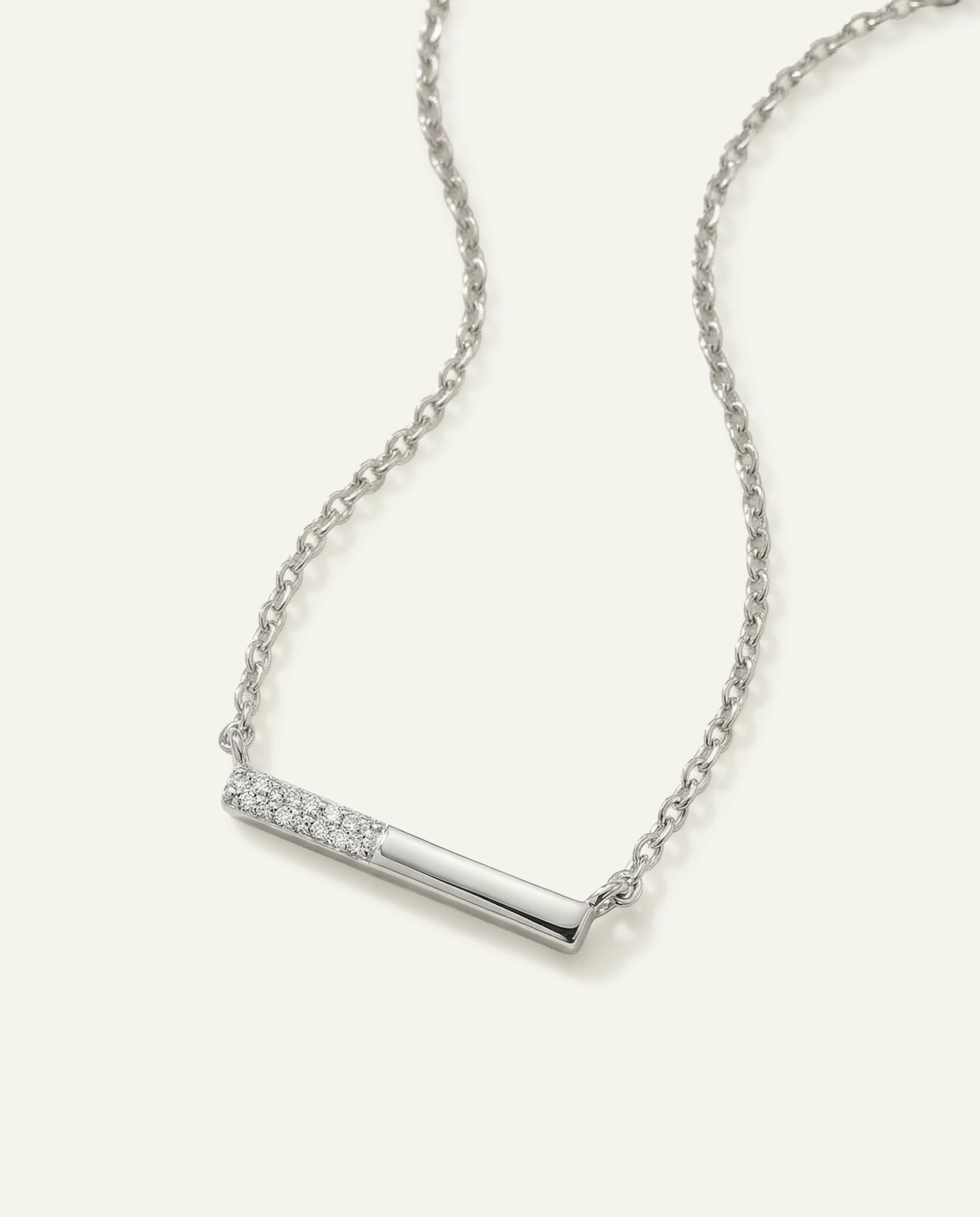 Silver necklace with a bar pendant on a light gray background