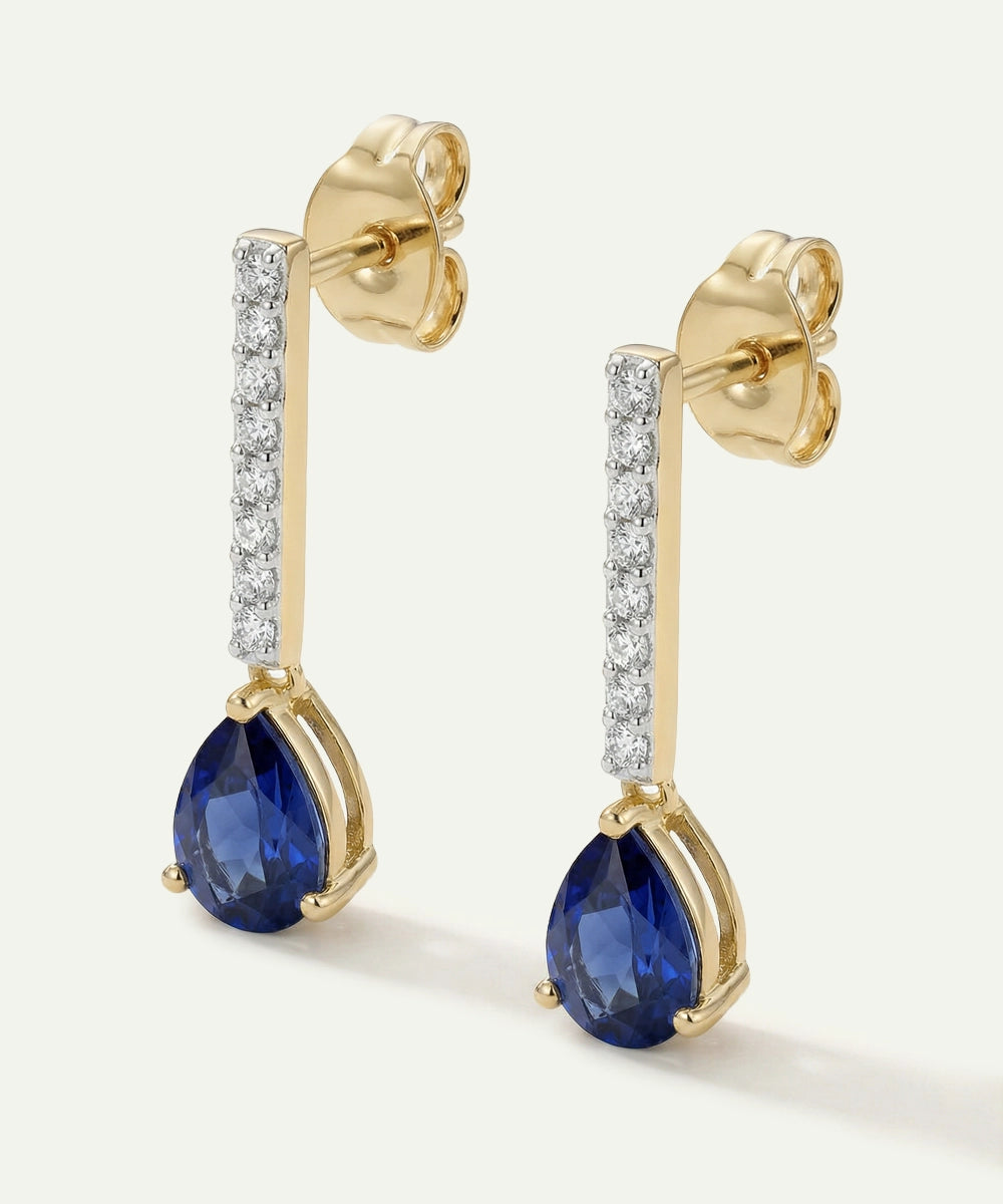 Gold earrings with blue gemstones and diamond accents on a white background