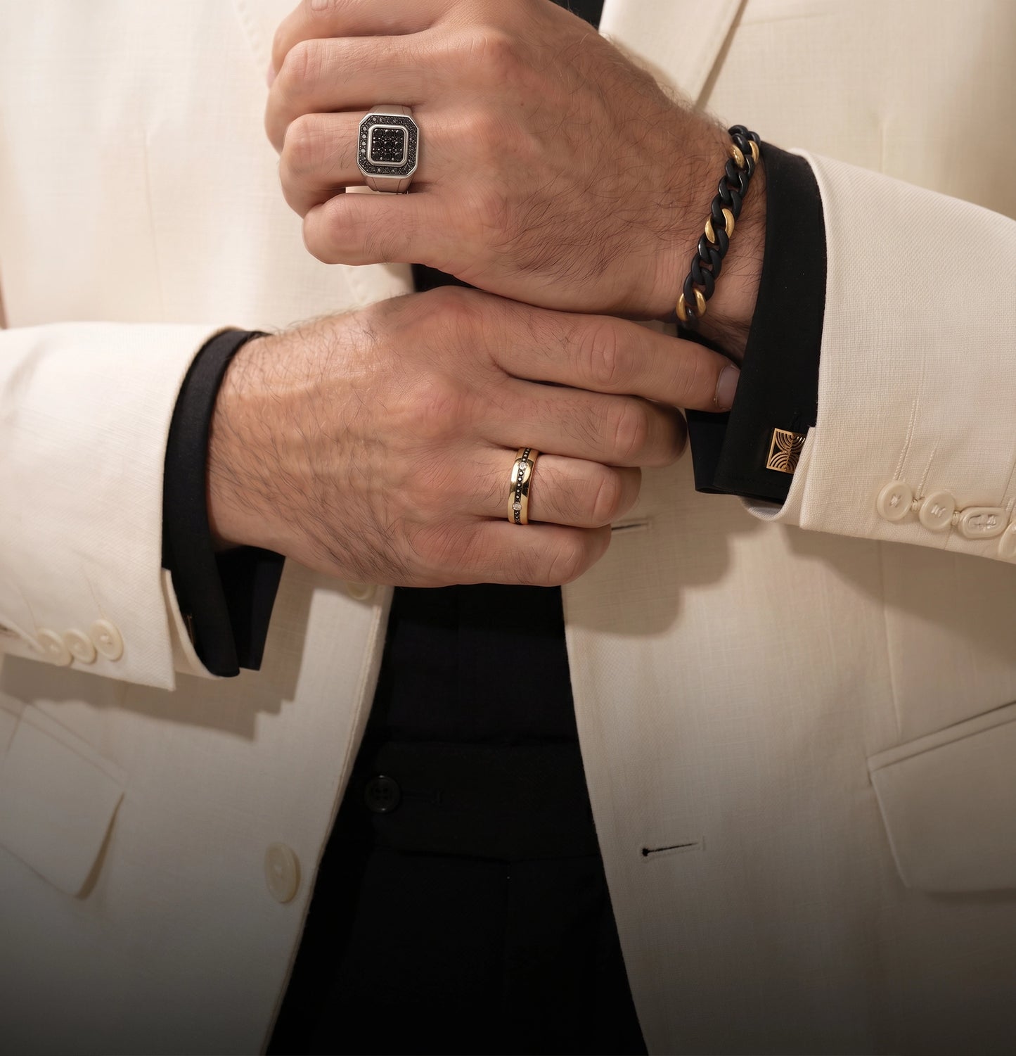 Close-up of a person wearing a white suit with jewelry on hands
