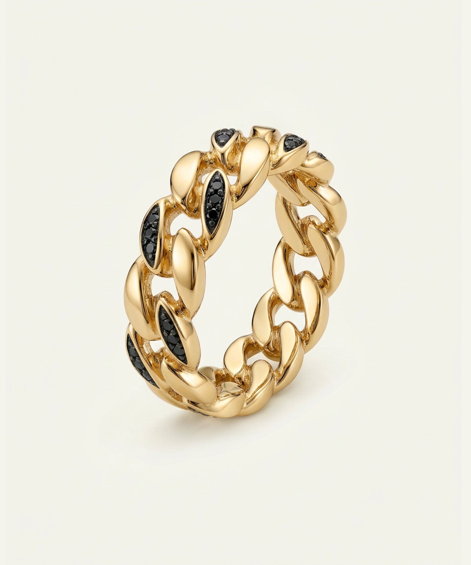 Gold chain-style ring with black gemstones on a light beige background