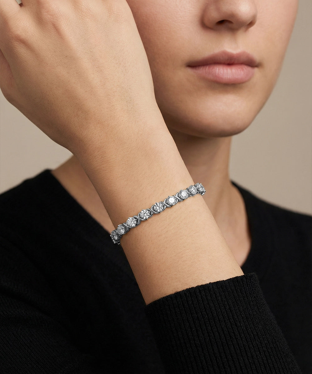 Close-up of a person wearing a diamond bracelet on a neutral background