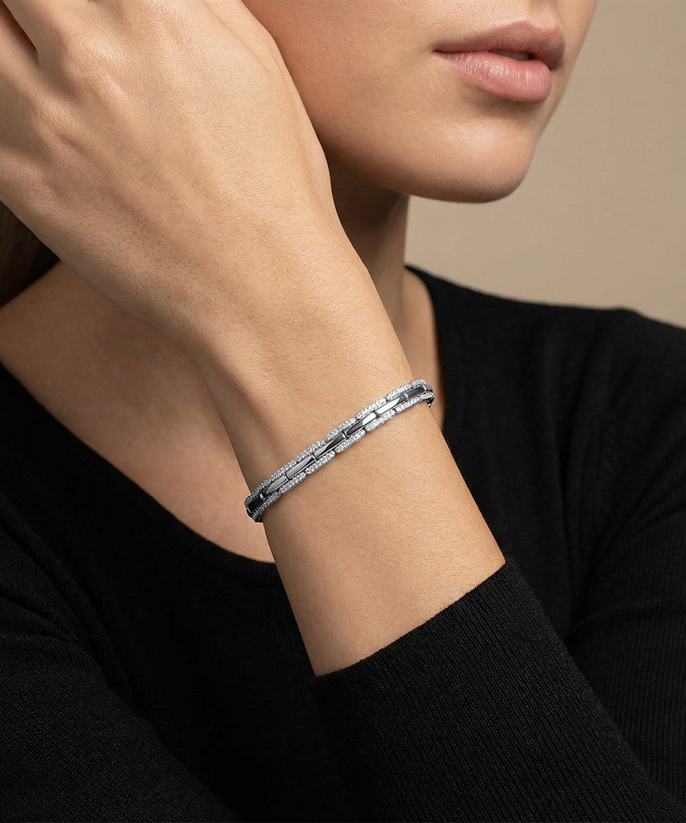 Silver bracelet on a person's wrist with a neutral background