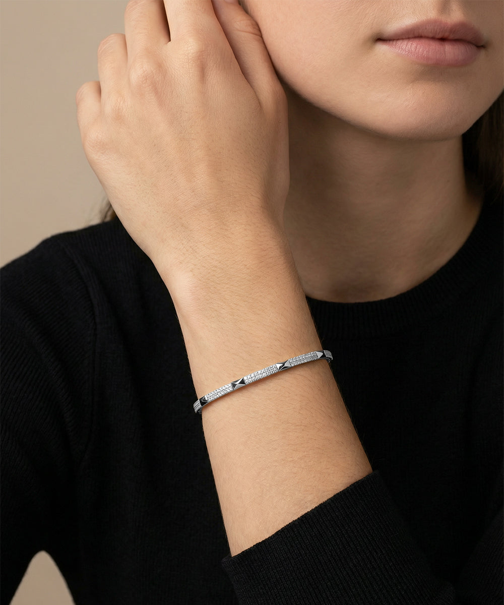 Silver bracelet on a person's wrist with a neutral background