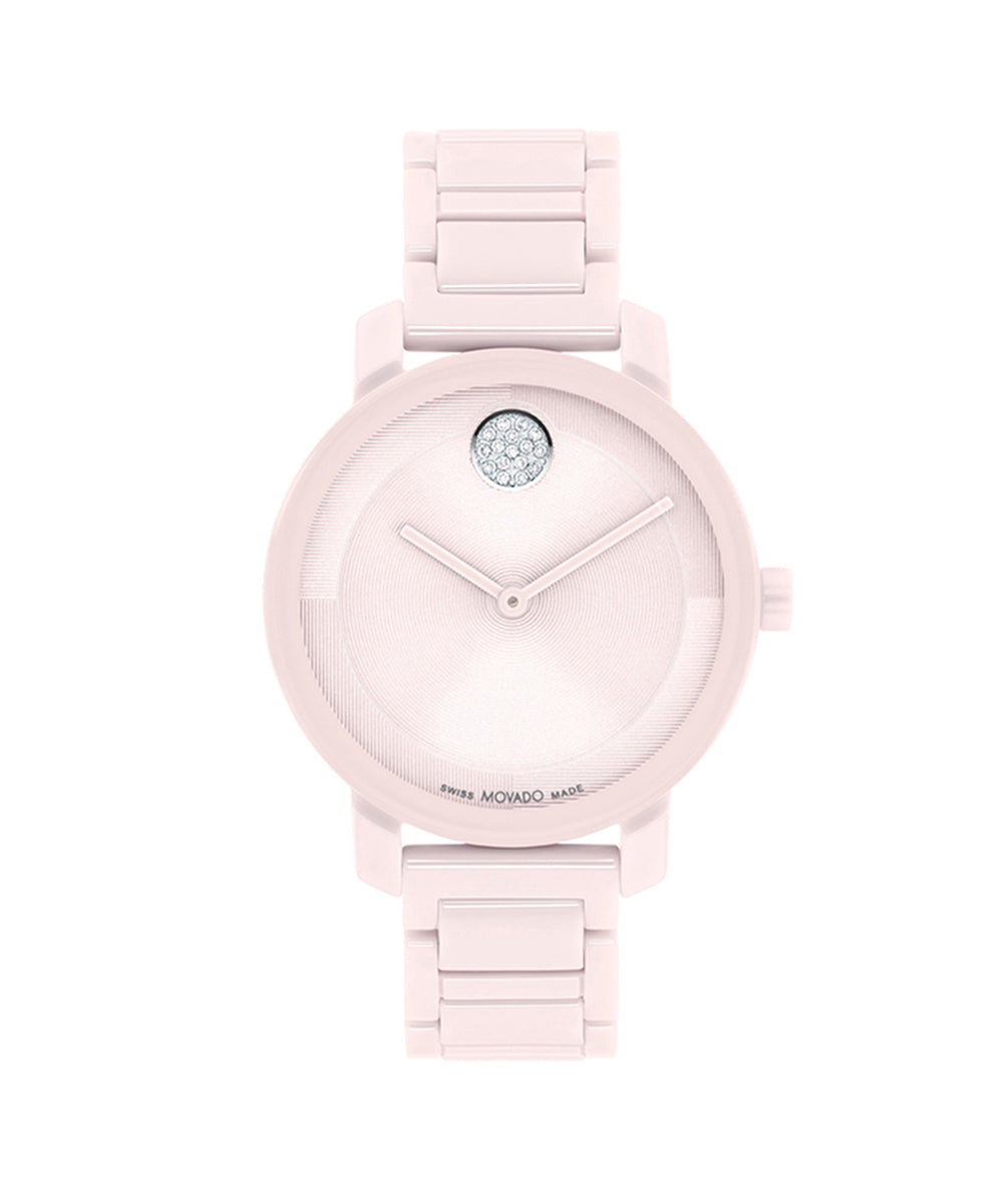 Pink watch with a gemstone on the face against a white background