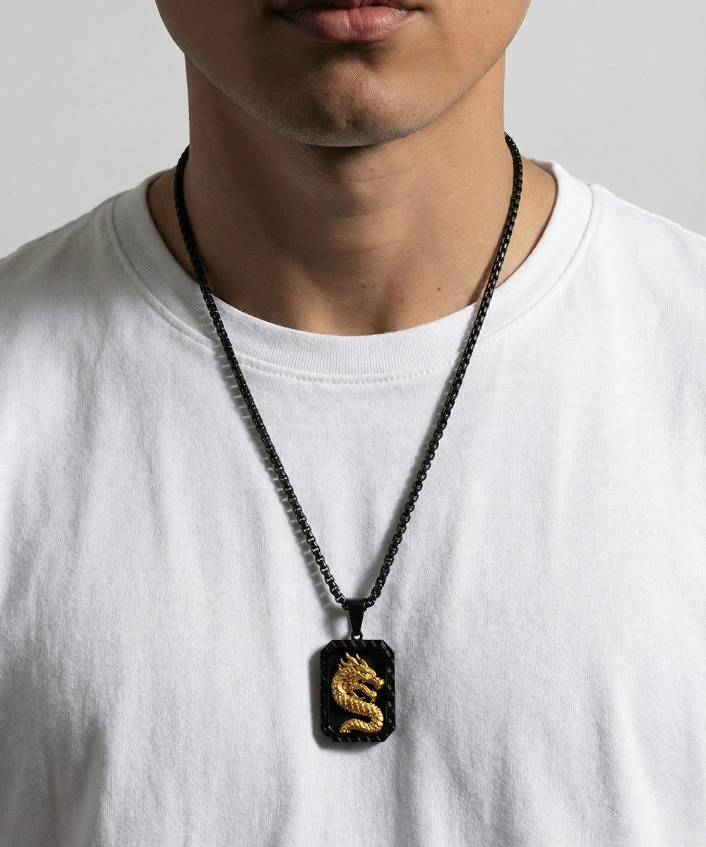 Person wearing a necklace with a dragon pendant on a plain background