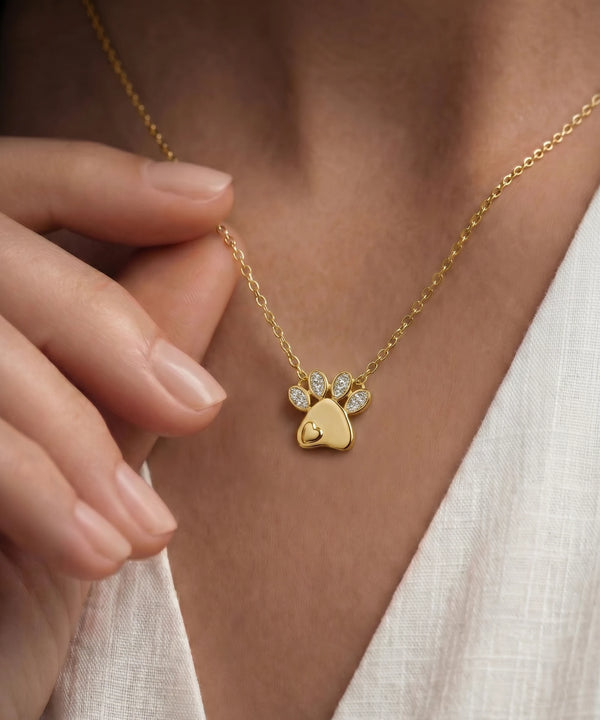 Gold necklace with a paw-shaped pendant worn by a person