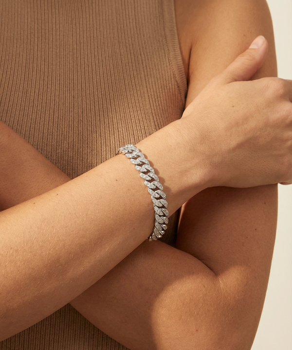 Silver bracelet on a person's wrist with a neutral background