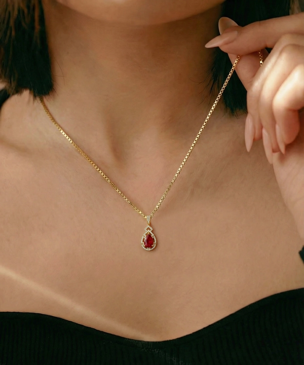 Gold necklace with a red pendant worn by a person