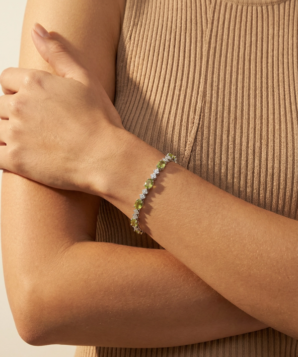 Close-up of a person wearing a bracelet with green beads on a beige background