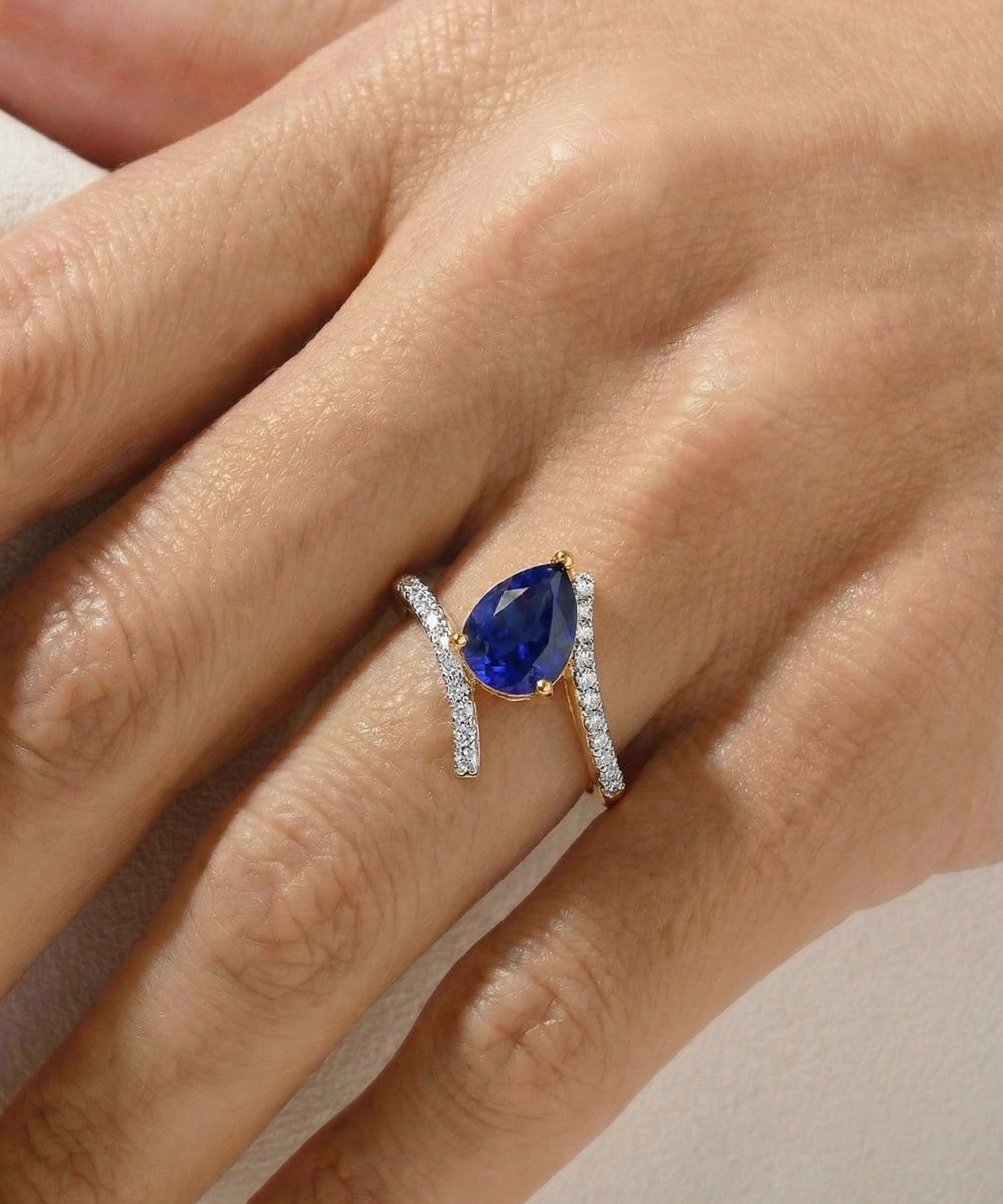 Ring with a blue gemstone on a hand against a neutral background
