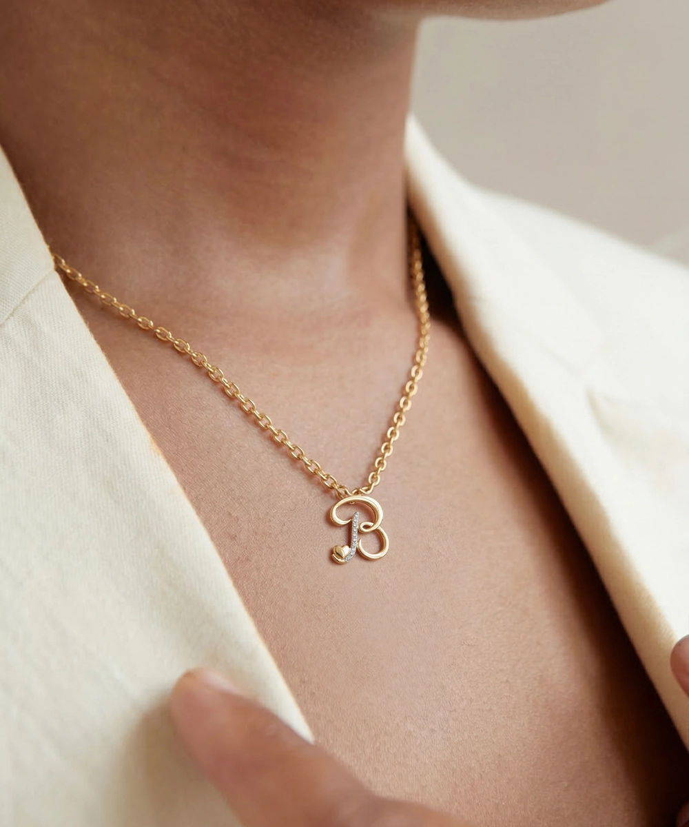 Gold necklace with a small pendant worn by a person in a cream-colored outfit.