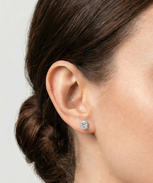 Close-up of an ear wearing a square-cut earring with a plain background