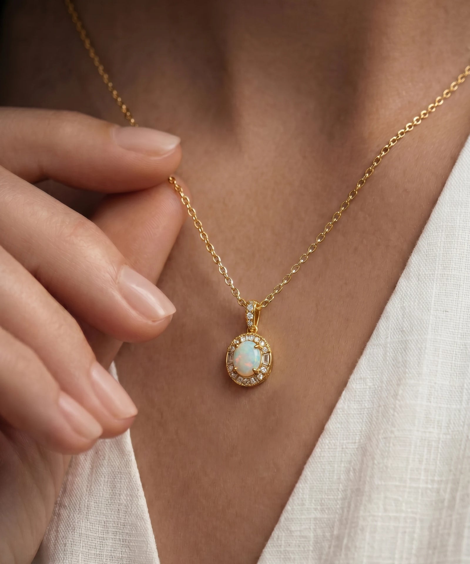 Gold necklace with an opal pendant worn by a person