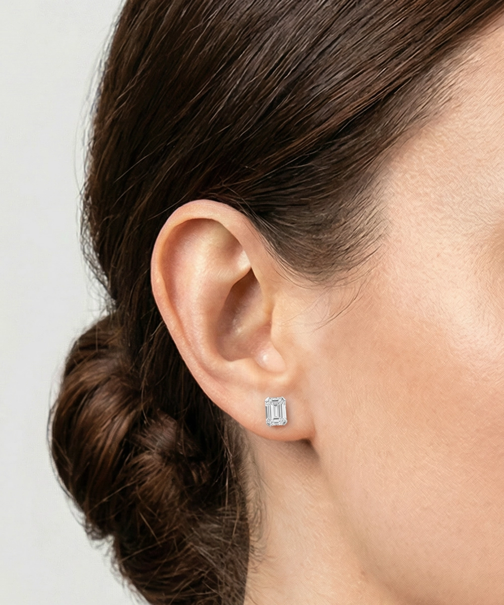 Close-up of an ear wearing a square-cut earring with a plain background