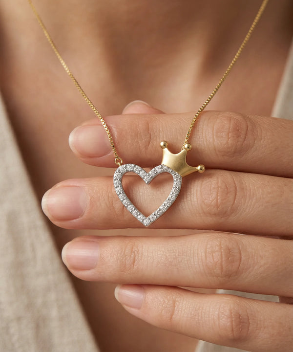 Heart-shaped necklace with a crown detail held between fingers