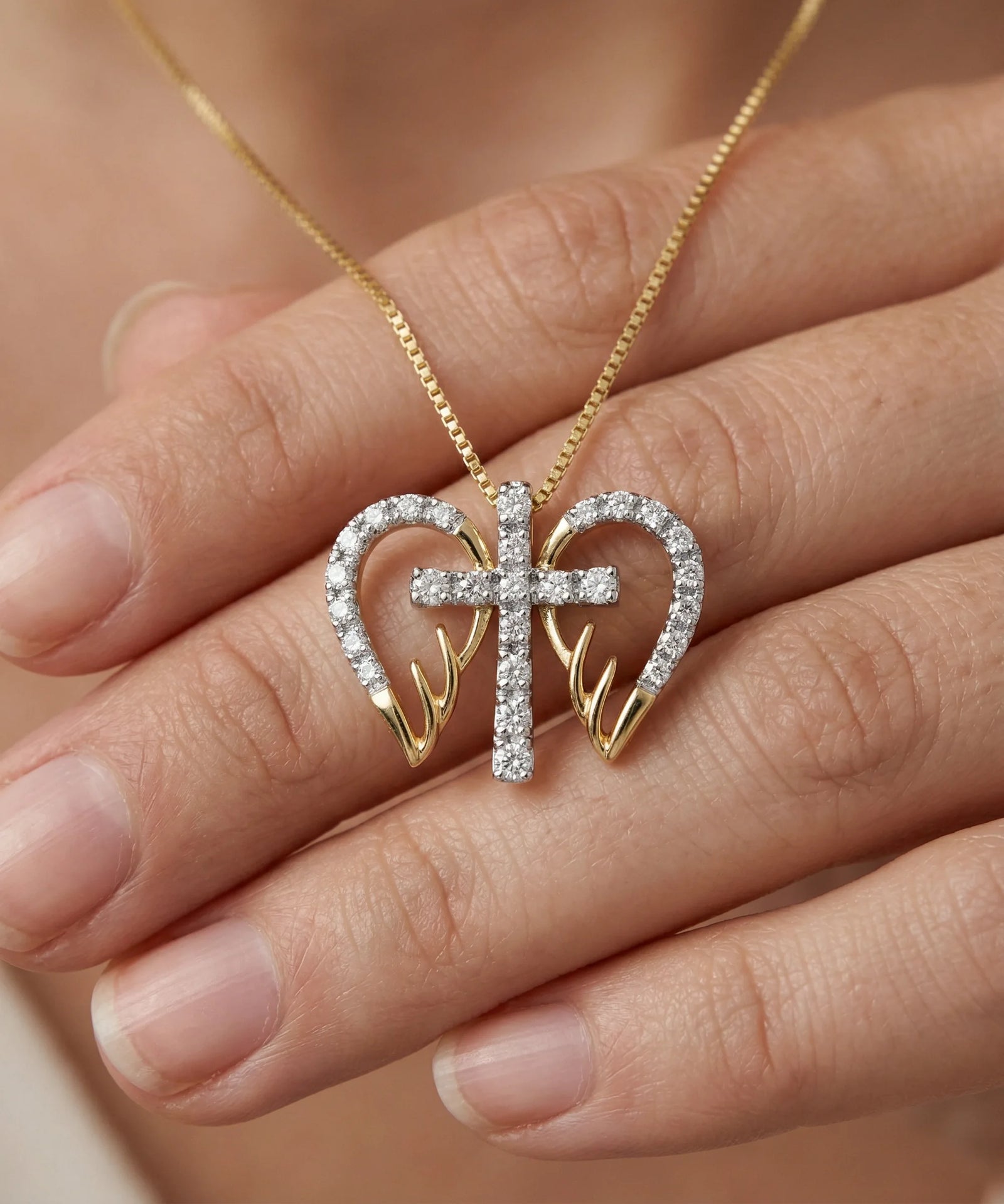 Gold necklace with a heart and cross pendant on a hand