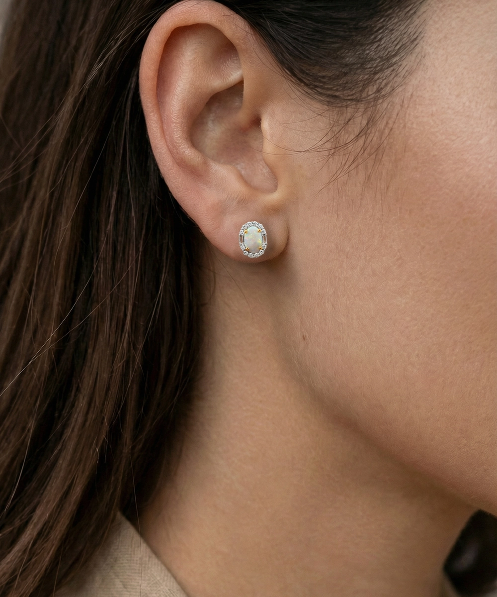 Close-up of an ear wearing a silver earring with a clear gemstone.