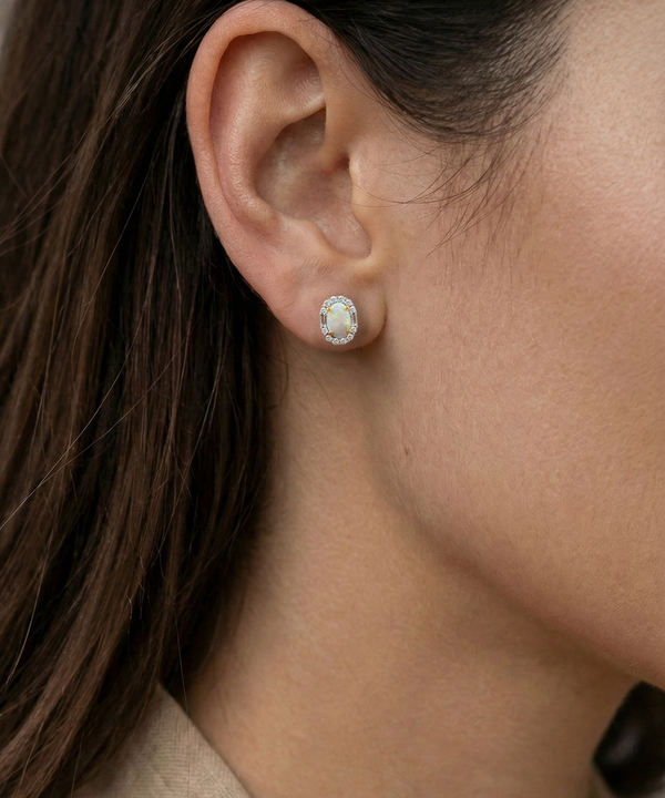 Close-up of an ear wearing a silver earring with a clear gemstone.