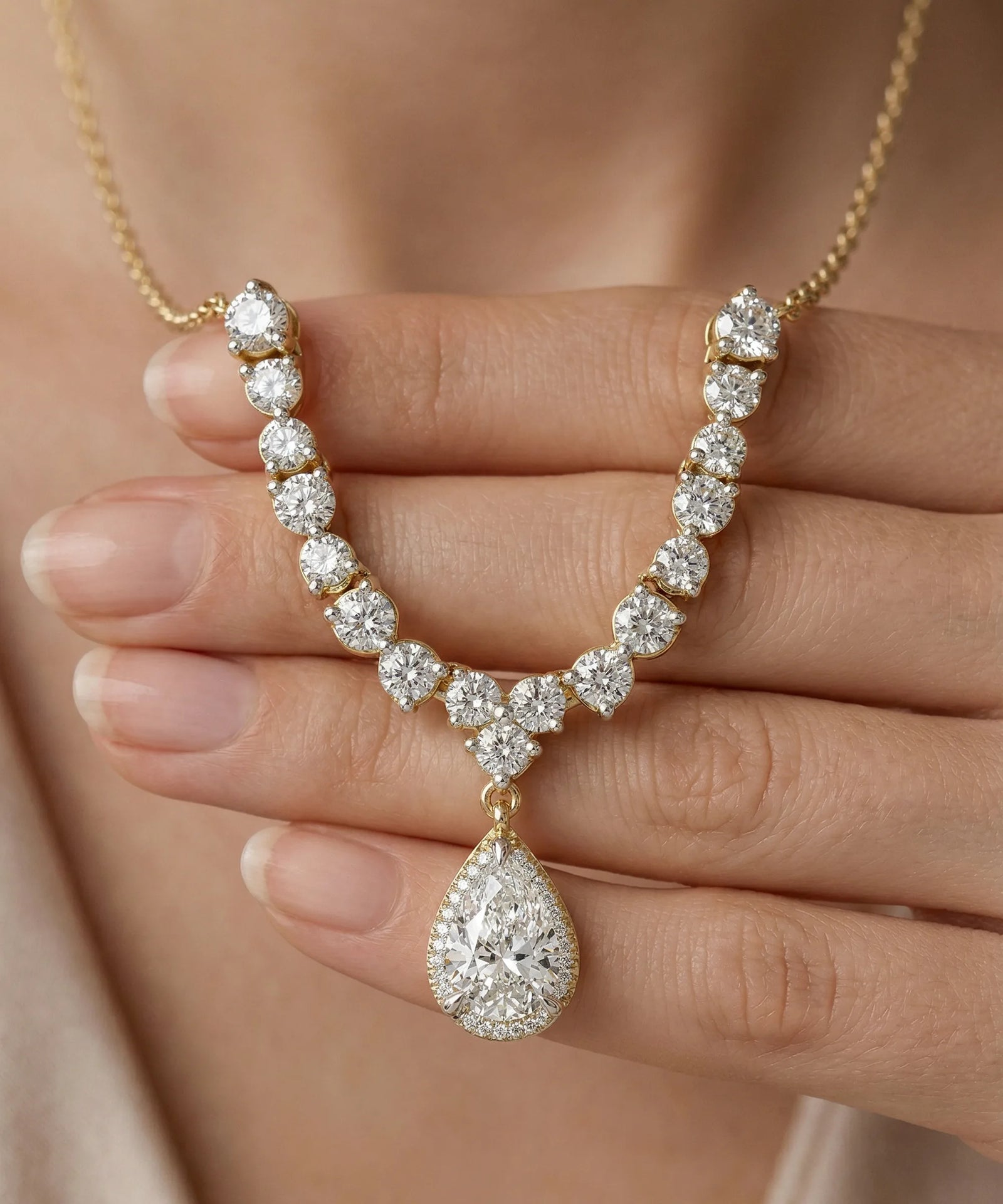 Diamond necklace held by a hand against a neutral background