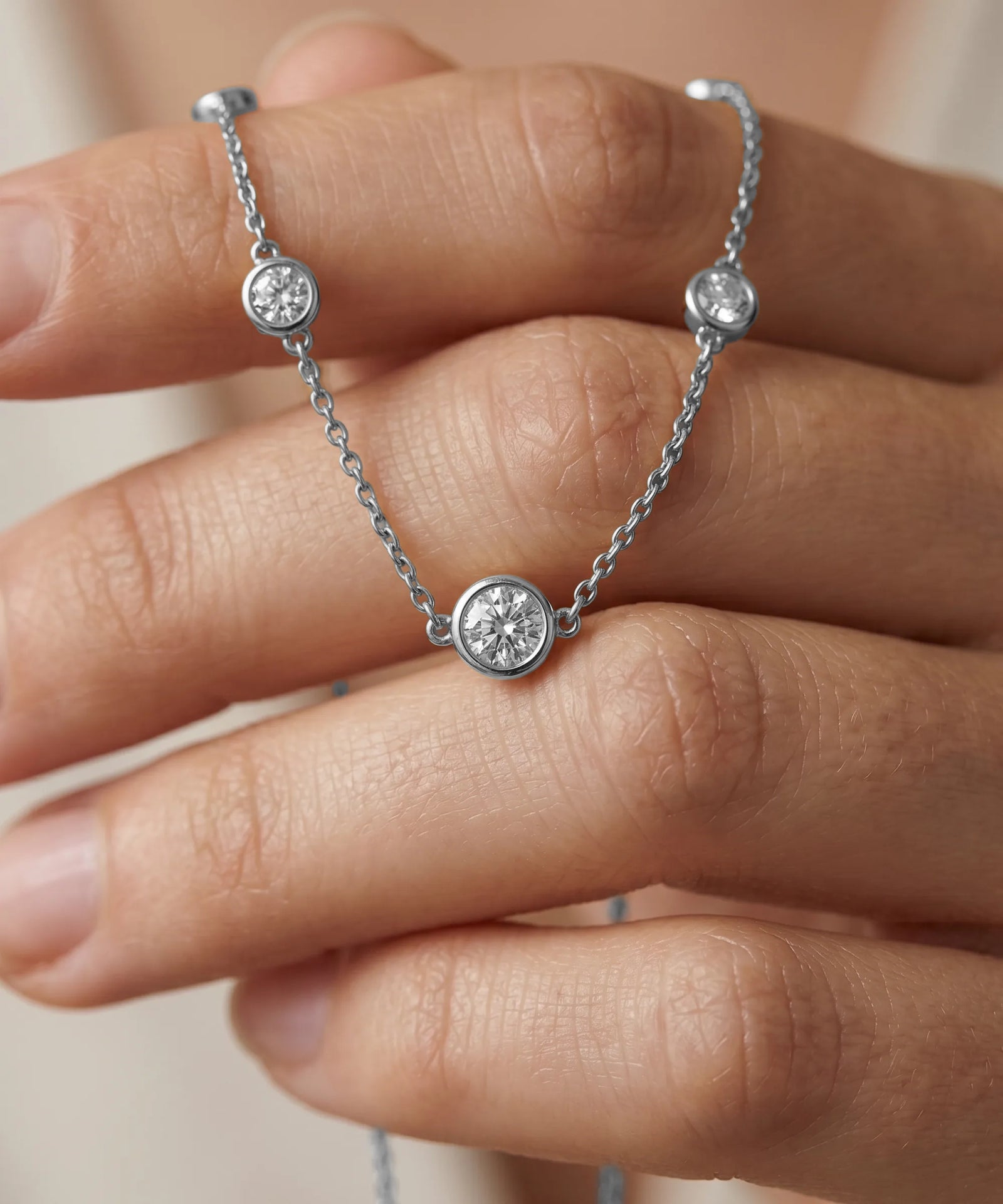Silver chain bracelet with diamond beads on a hand against a neutral background