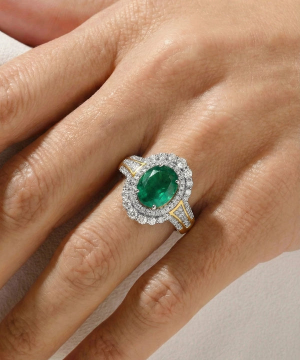 Emerald ring with diamond halo on a hand against a neutral background