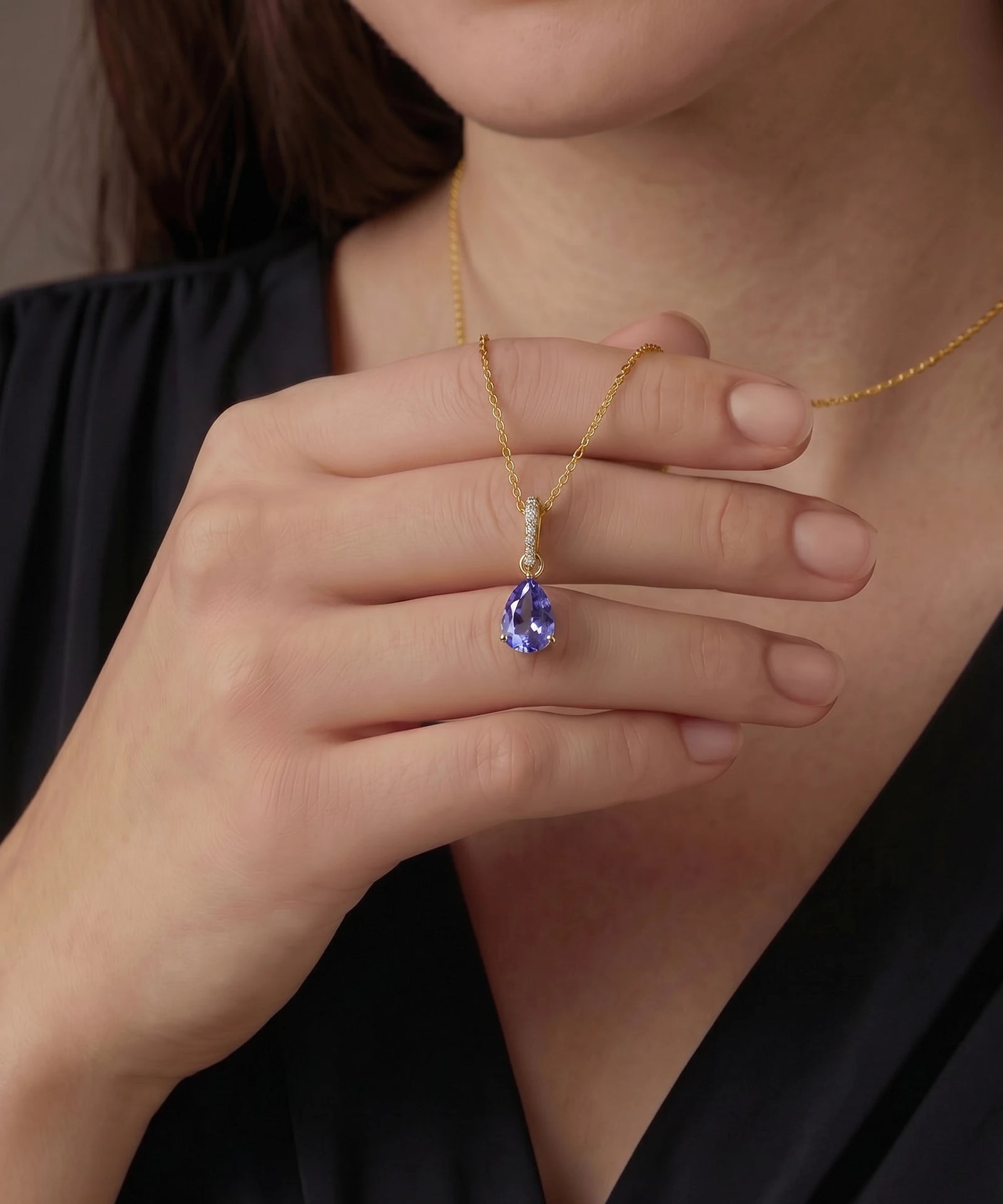 Gold necklace with a blue gemstone pendant worn by a person