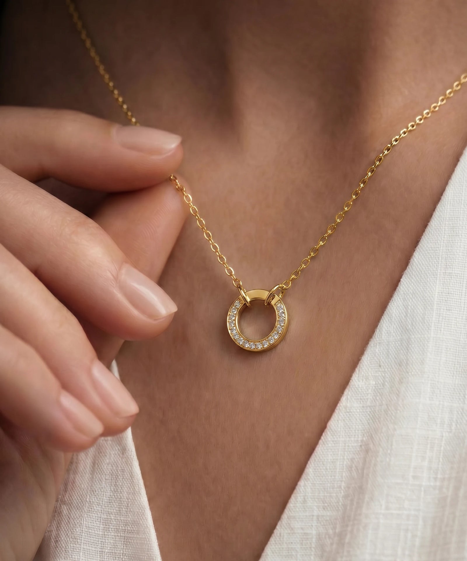 Gold necklace with a circular pendant worn by a person