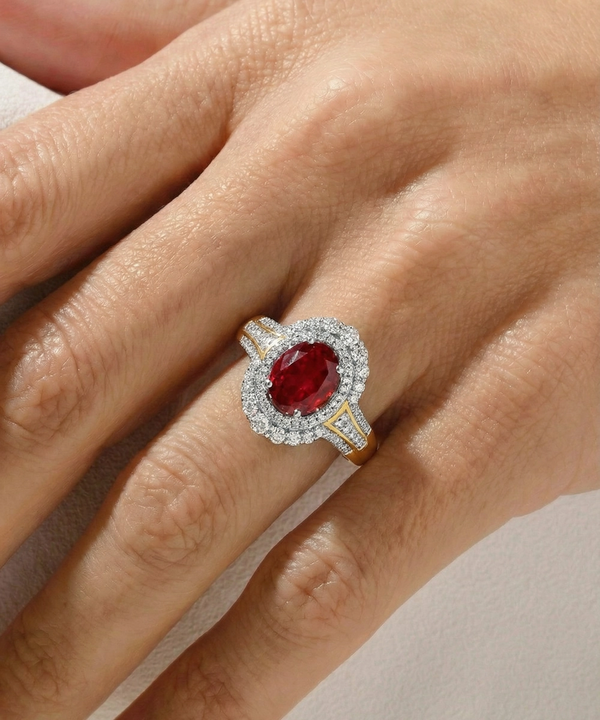 Ring with a red gemstone and diamond accents on a hand against a neutral background