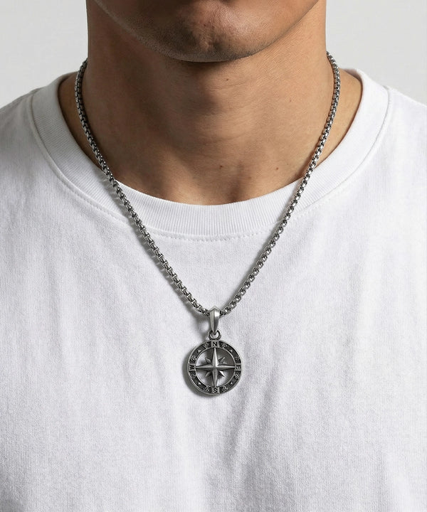 Necklace with a compass pendant worn by a person on a white background