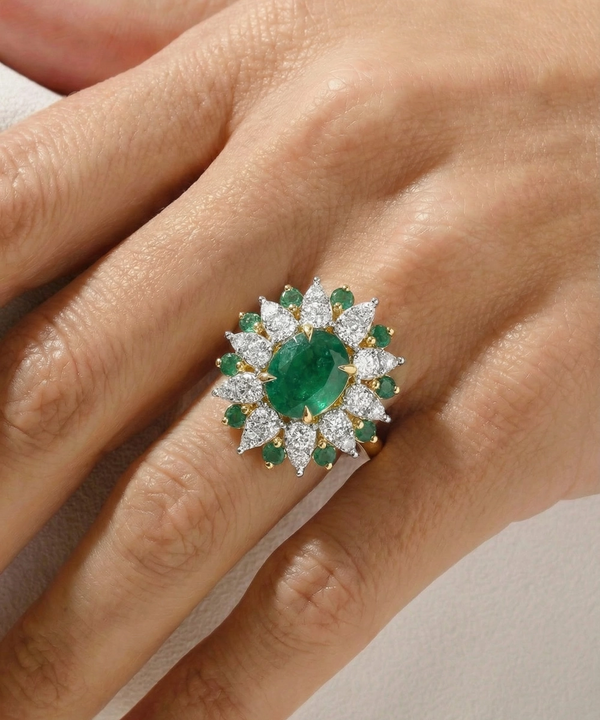 Emerald and diamond ring on a hand against a neutral background