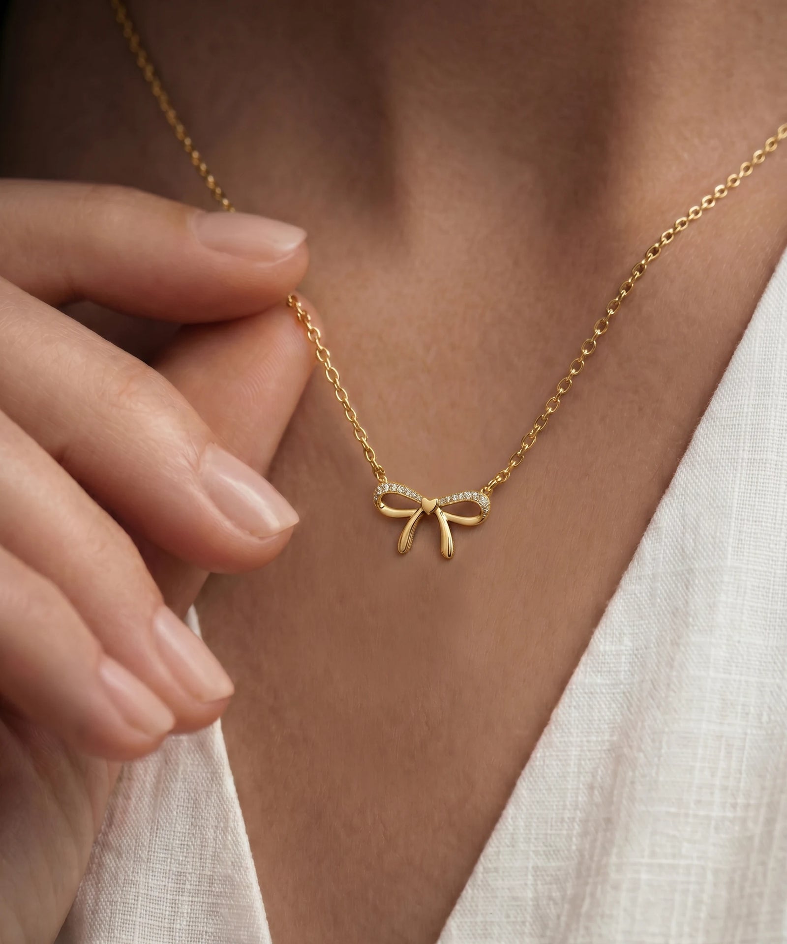 Gold bow-shaped necklace with diamonds on a person's neck