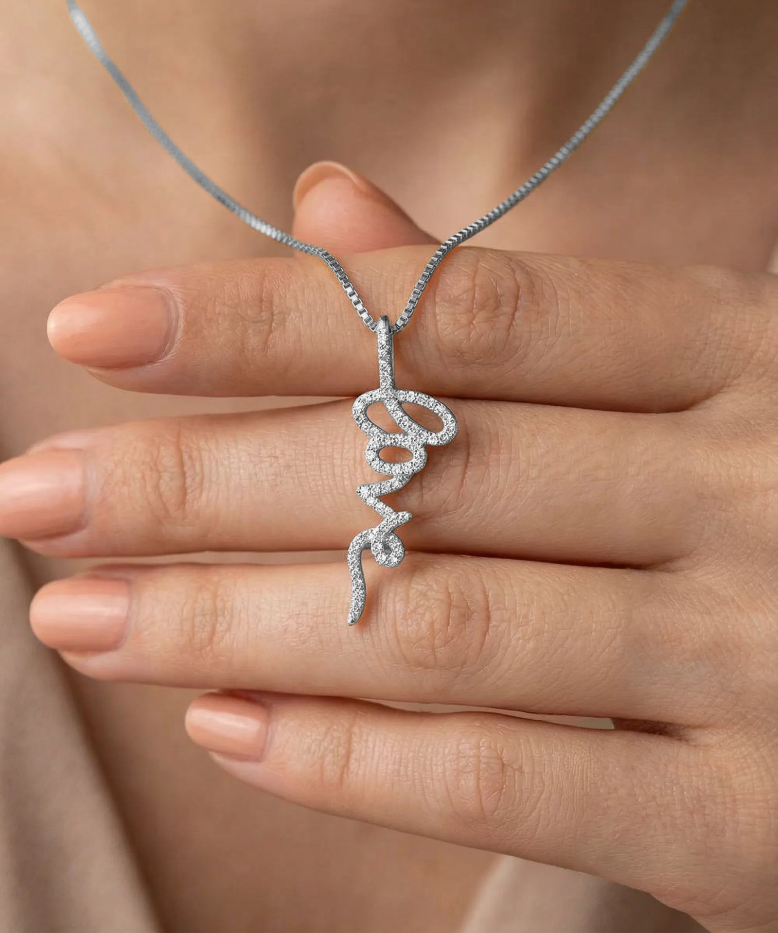 Silver snake-shaped pendant on a chain held between fingers