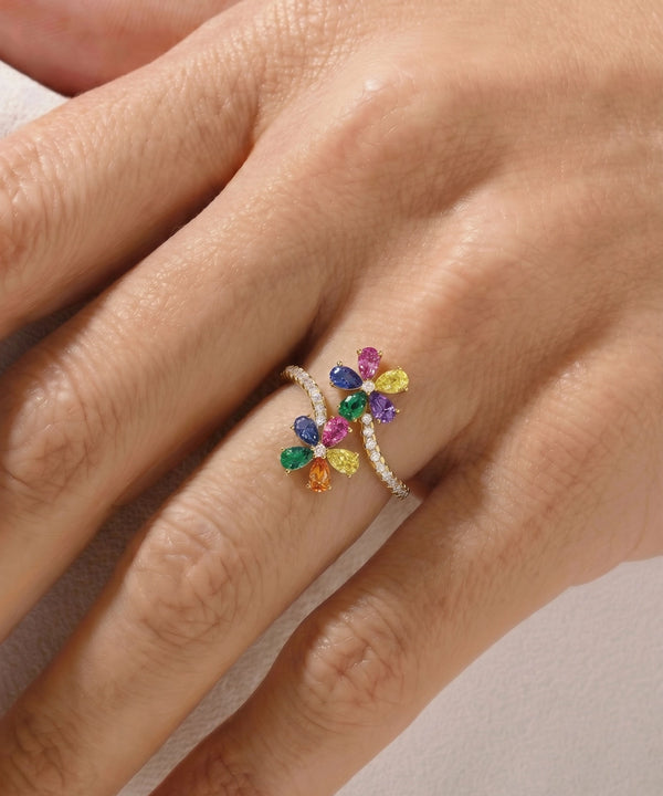 Multicolored gemstone ring on a hand against a neutral background