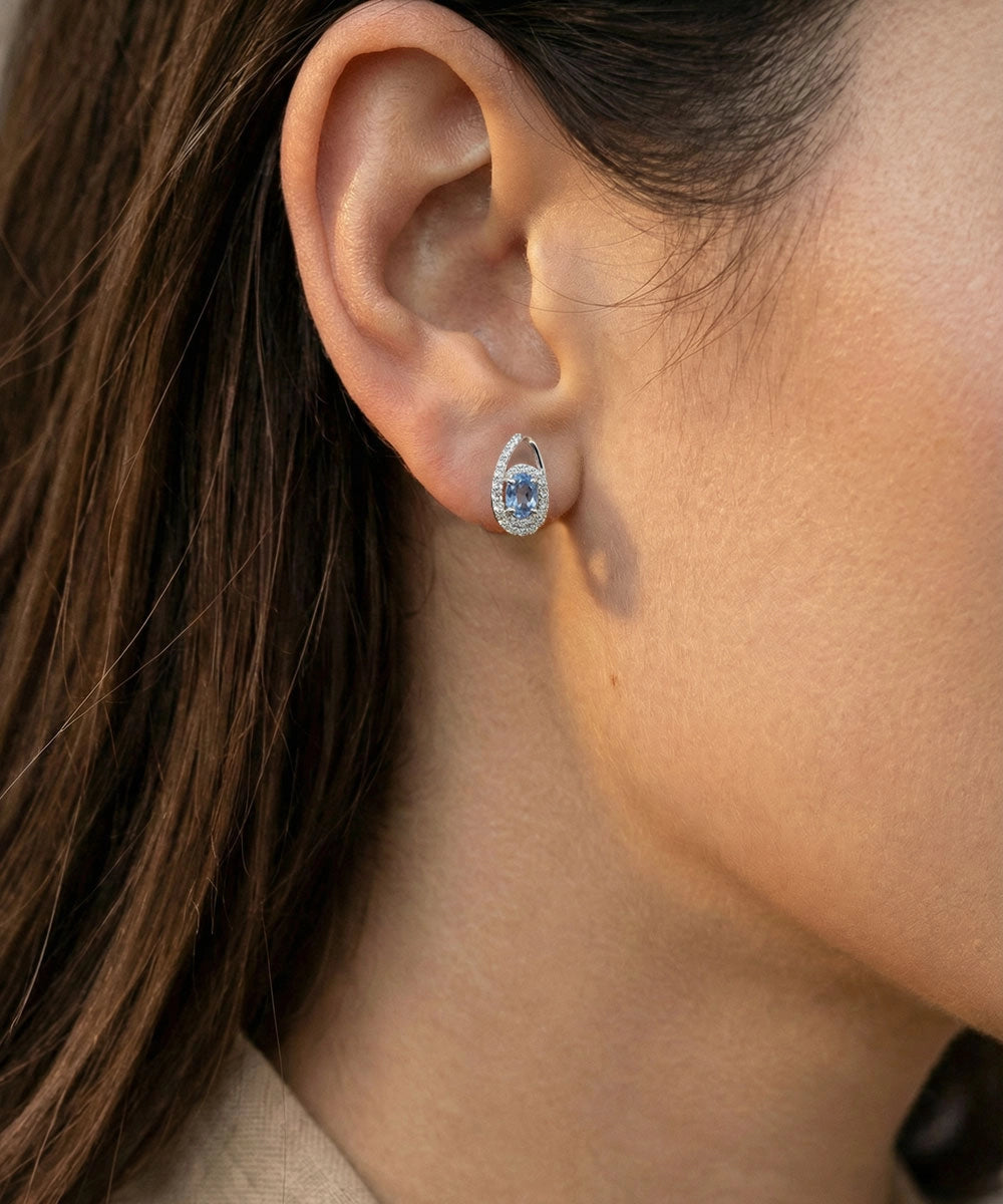 Close-up of an ear wearing a diamond earring with a blurred background