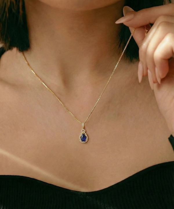 Gold necklace with a blue pendant worn by a person