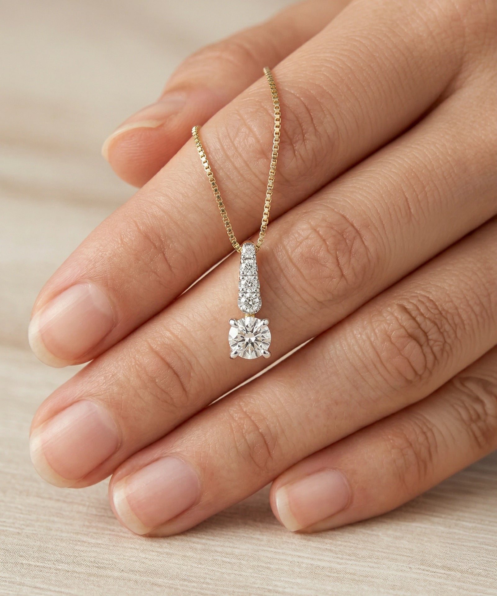 Diamond necklace on a hand against a neutral background