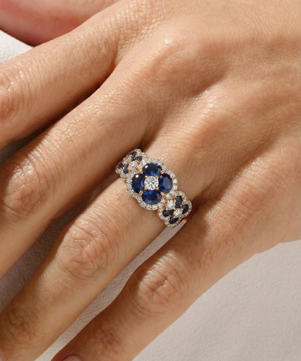 Close-up of a hand wearing a decorative ring with blue stones and white accents.
