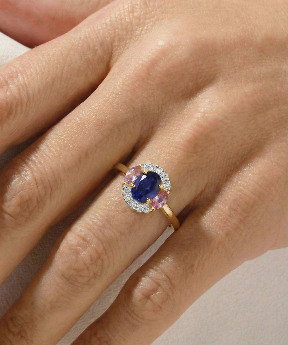 Ring with a blue gemstone and pink accents on a hand against a neutral background